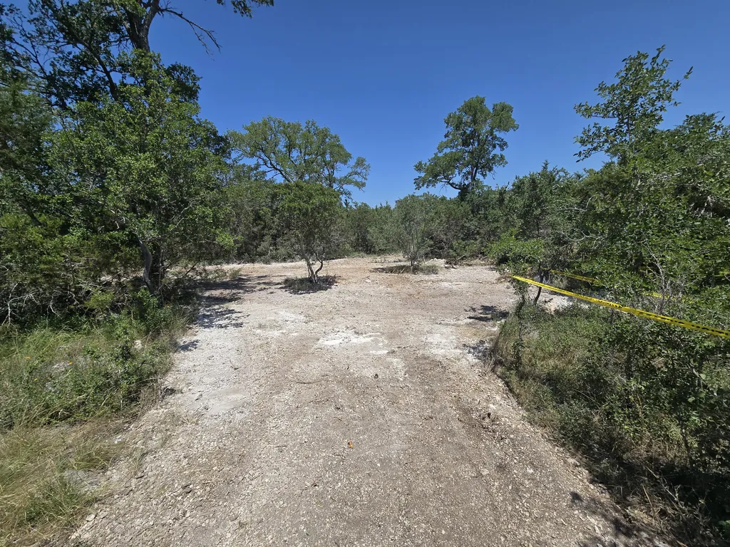 Graded caliche drive cut through brush and small trees, land grading