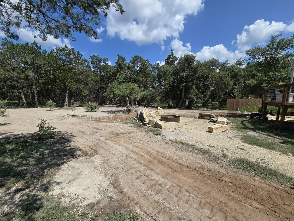 Graded, level caliche ground around a stone fire pit under oaks, land grading