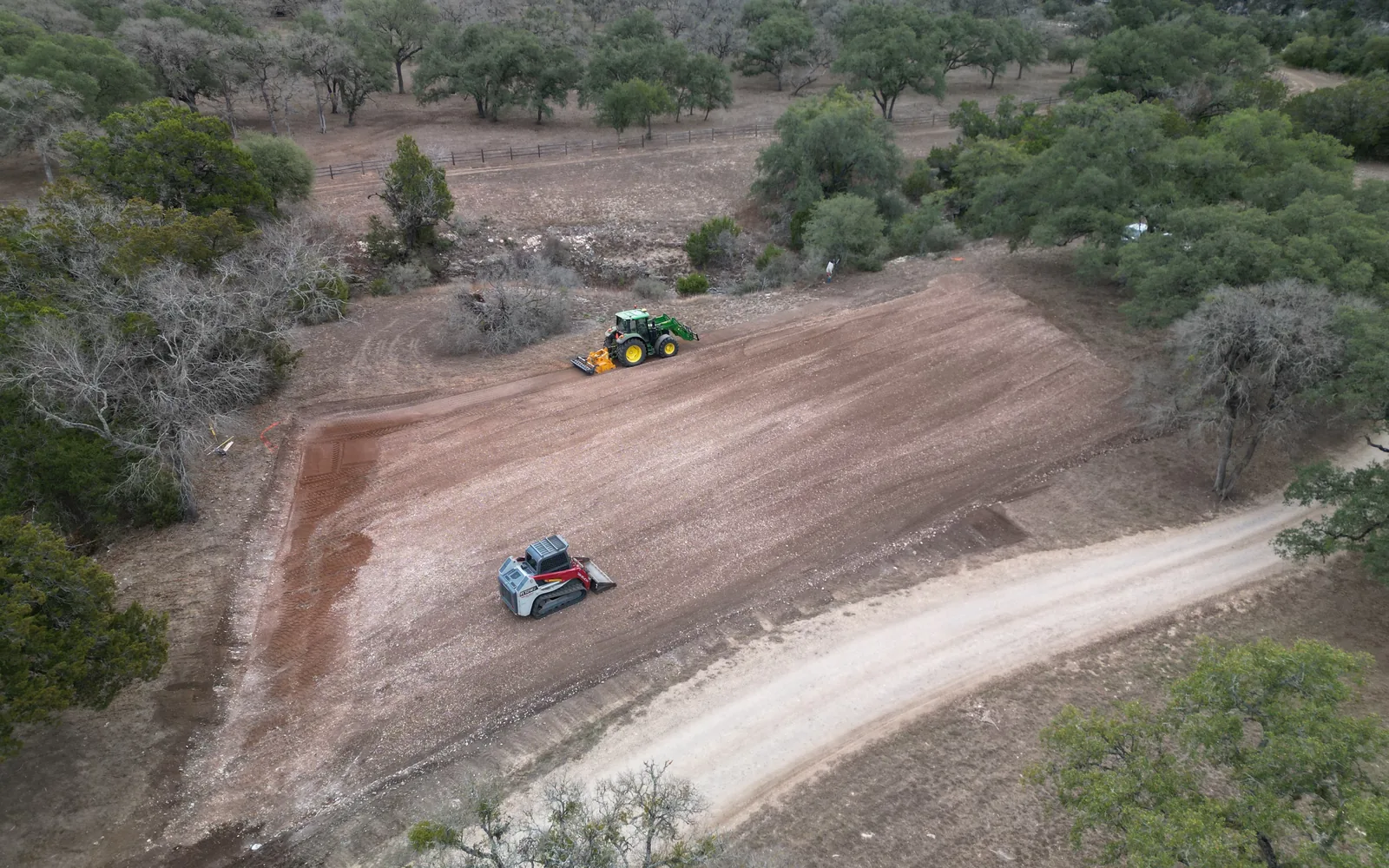 Aerial view of a freshly milled pad with a tractor rock mill and a tracked skid steer at work, rock milling