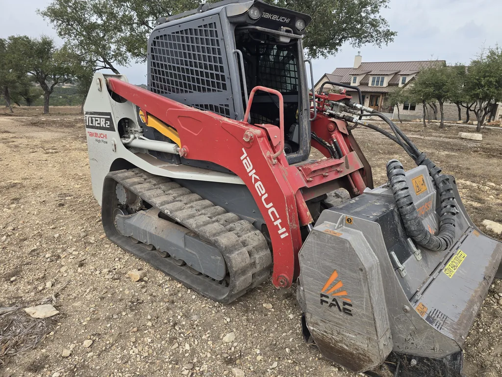 Tracked skid steer with a crusher attachment on crushed rock ground, rock milling and rock crushing