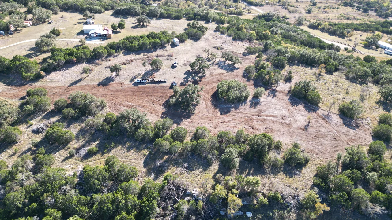 Aerial view of a cleared ranch property with a truck and trailer on the job, land clearing