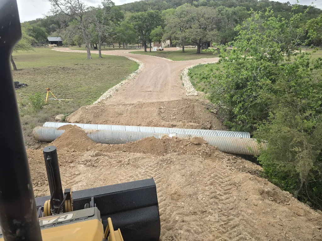 New culvert pipes set under a ranch road crossing with fill dirt over them, site work