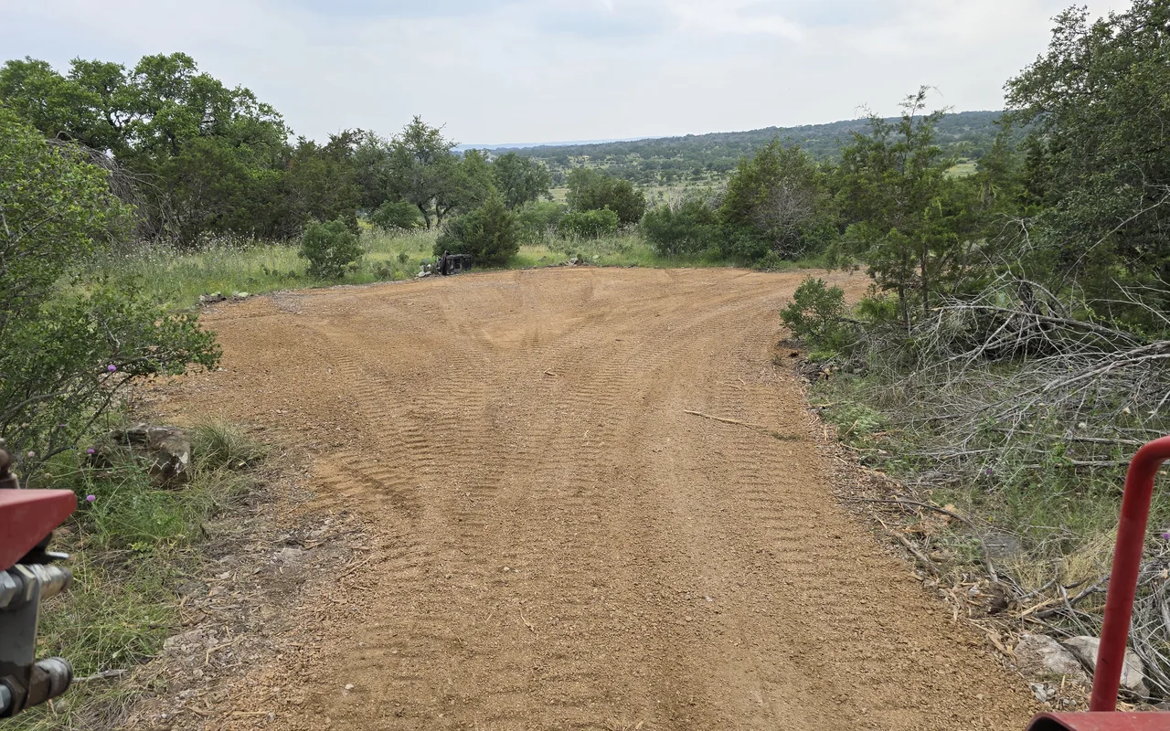 Freshly graded road cut through cedar and oaks, site work